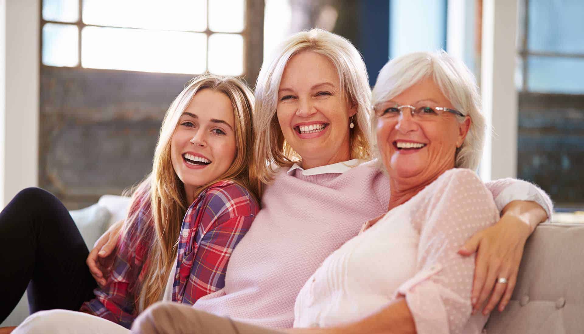 Grandmother with mother and adult daughter smilling.